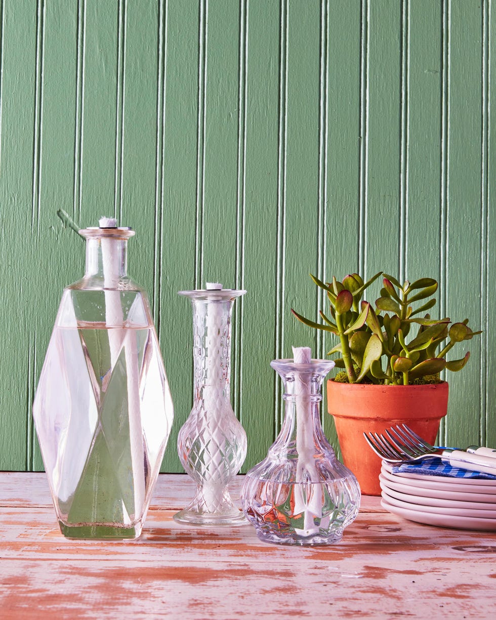 vintage vases filled with citronella oil and large wicks set on a table