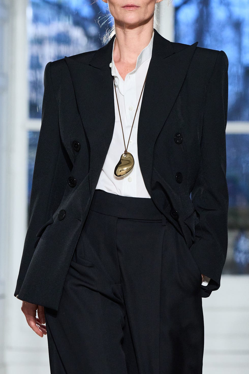 Fashion model in a tailored black outfit with a white shirt and a statement necklace