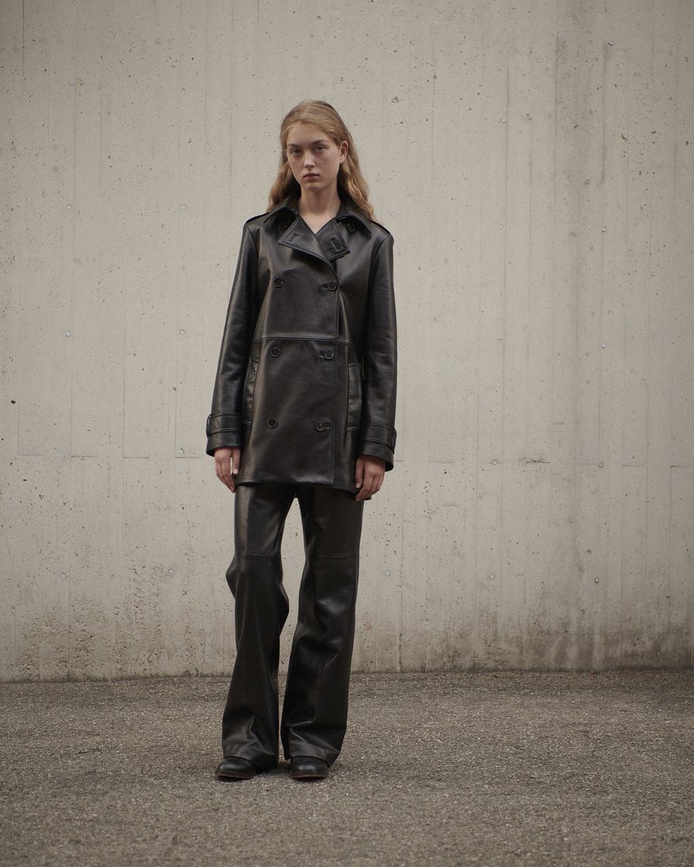 a veronica de piante model wears leather trousers and a leather jacket in front of a concrete wall