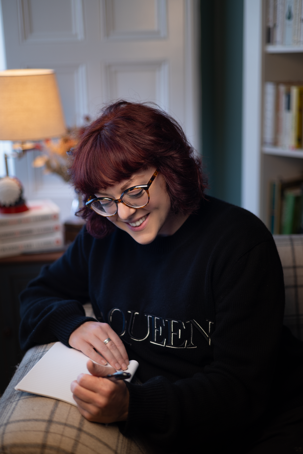 author ve schwab sits smiling and writes in a journal