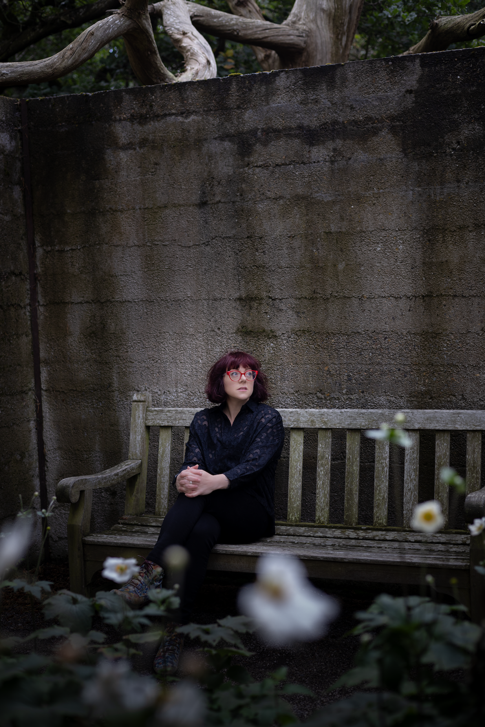 author ve schwab sitting on a bench in a garden