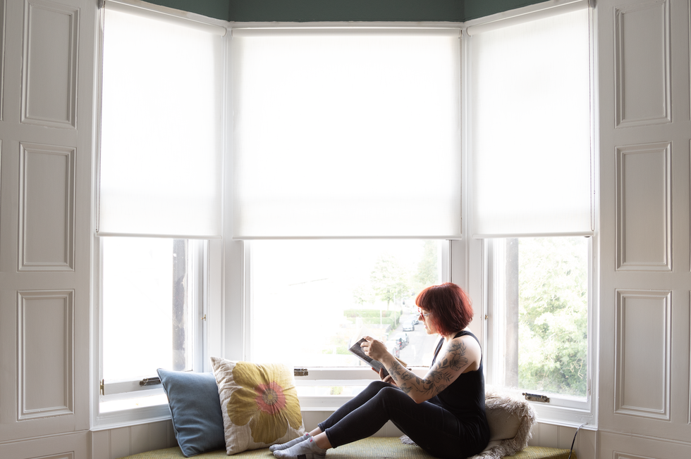 author ve schwab sits on a couch reading a book