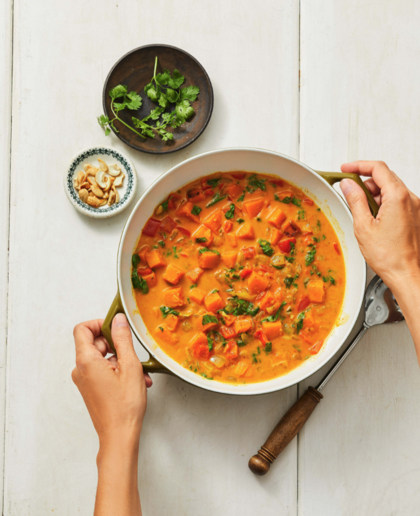 butternut squash curry on a white surface with hands