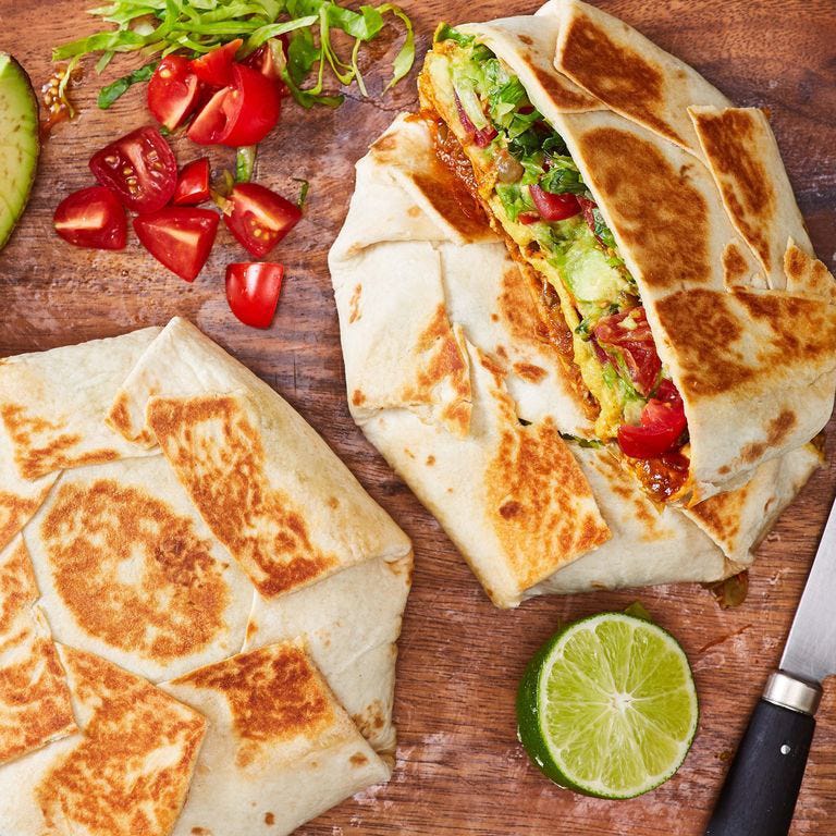vegan crunchwrap supreme filled with cooked lentils, avocado, tomatoes, and vegan cheese sauce