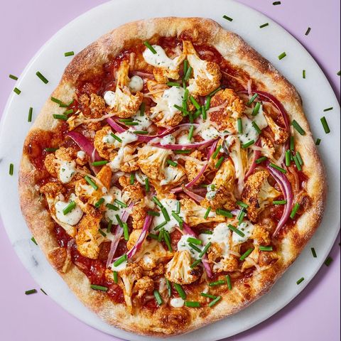 vegan bbq cauliflower pizza topped with red onions, ranch dressing, and chives