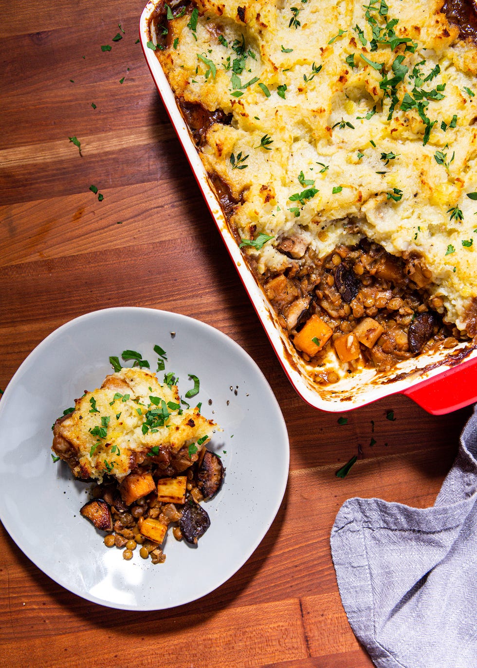 piece of vegan shepherds pie on a blue plate next to a baking dish full of vegan shepherds pie