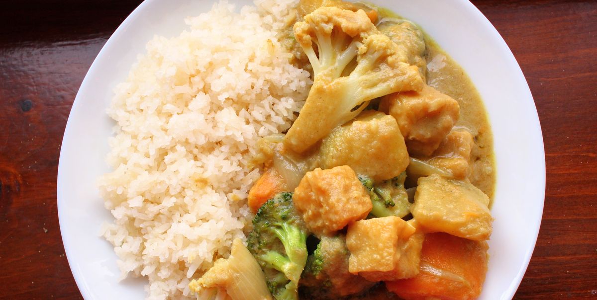 a shallow bowl of sticky white rice and sweet potato curry with cauliflower and broccoli and tofu puffs