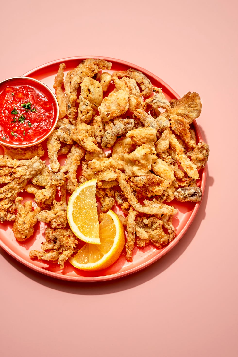 mushroom calamari on a pink plate with marinara sauce and lemon wedges