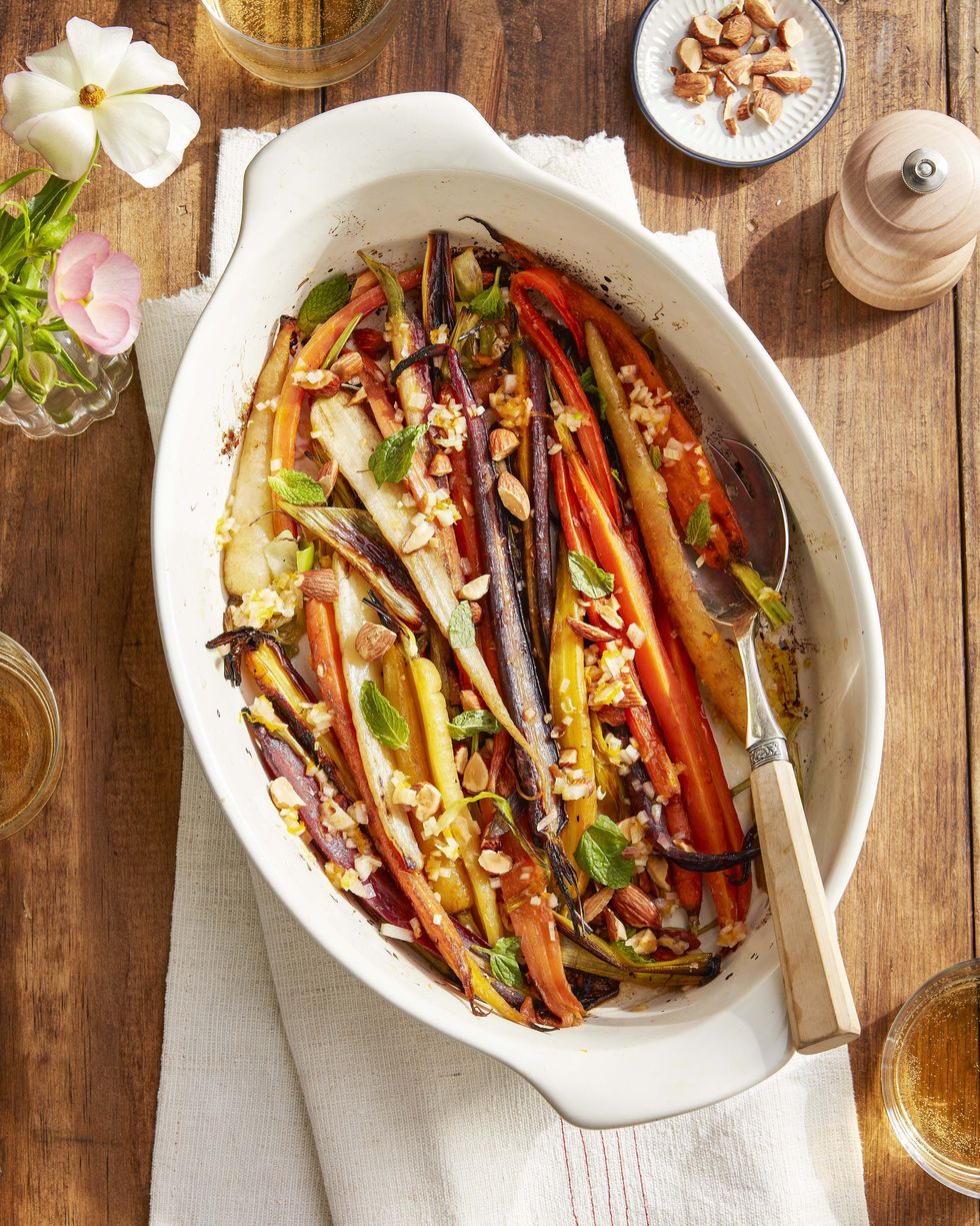 oven braised rainbow carrots in a white oval baking dish with a serving fork