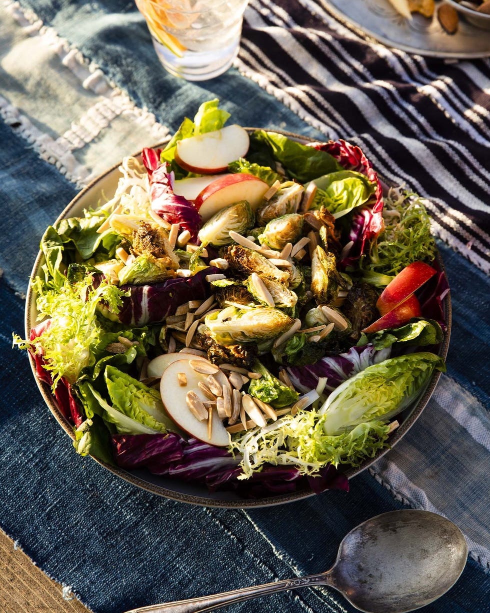 crispy brussels sprouts salad in a bowl on a dark blue and white striped tablecloth