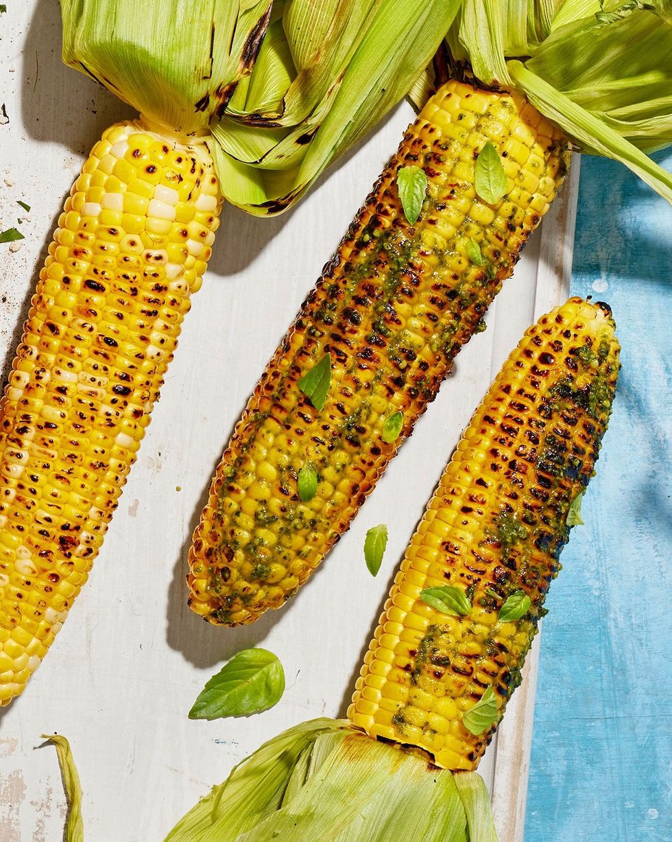 grilled corn with pesto and basil schmear arranged on a white wooden serving board