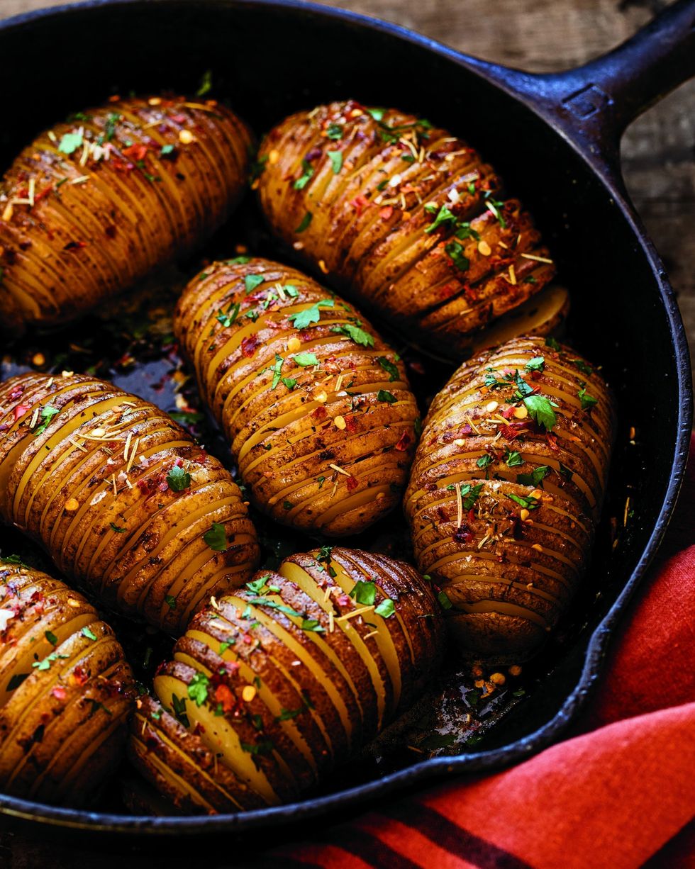 hasselback potatoes made in a cast iron skillet and topped with chopped parsley