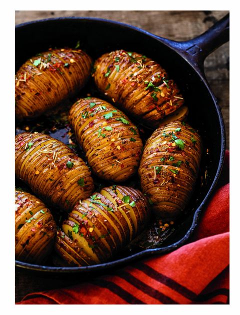 hasselback potatoes made in a cast iron skillet and topped with chopped parsley