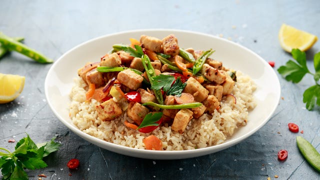 vegetarian meat free mycoprotein pieces vegetable stir fry, brown rice served in white plate