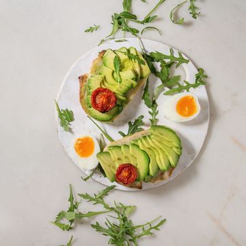 vegetarian sandwich with sliced avocado sun dried tomatoes egg arugula served on ceramic board over white marble background flat lay space