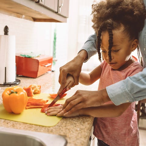mom helping daughter slice peppers