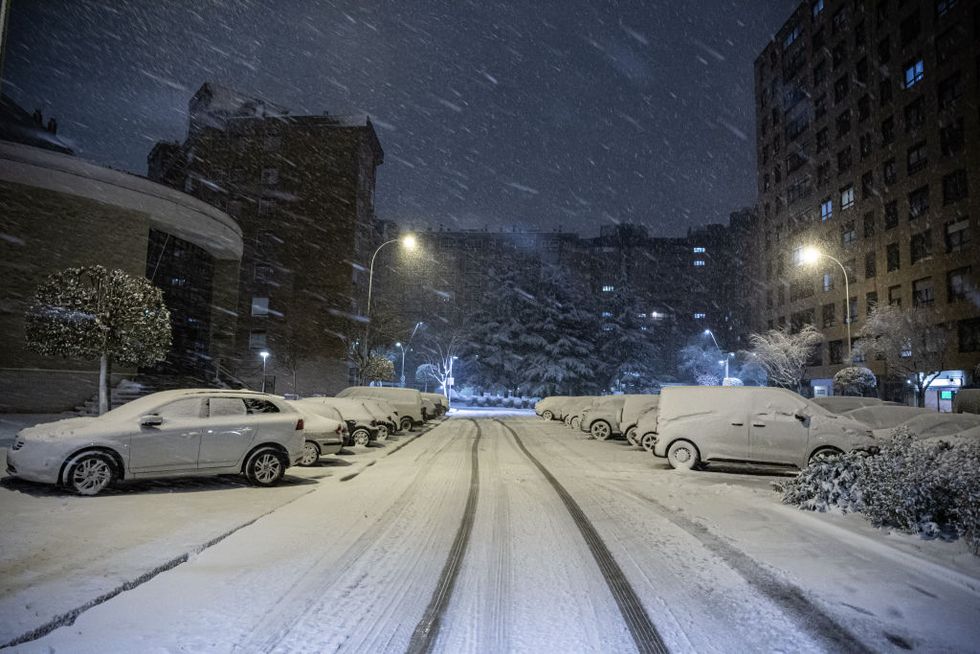 vehicles seen parked on a snow covered street following the