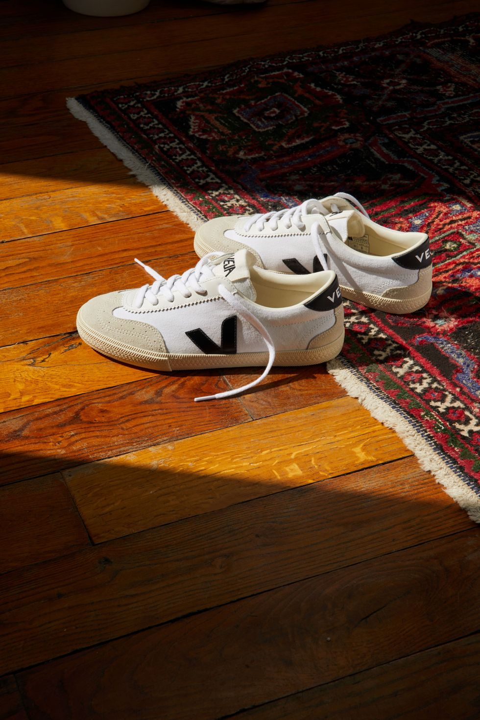a pair of white sneakers on a rug