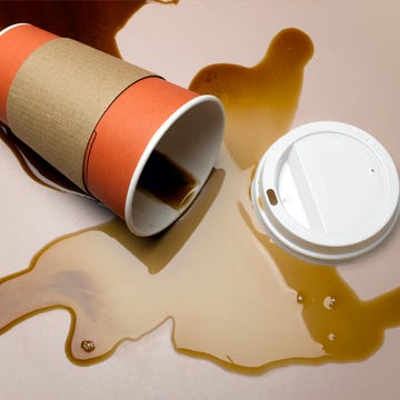 vending cup on side spilling coffee onto surface, elevated view, close up