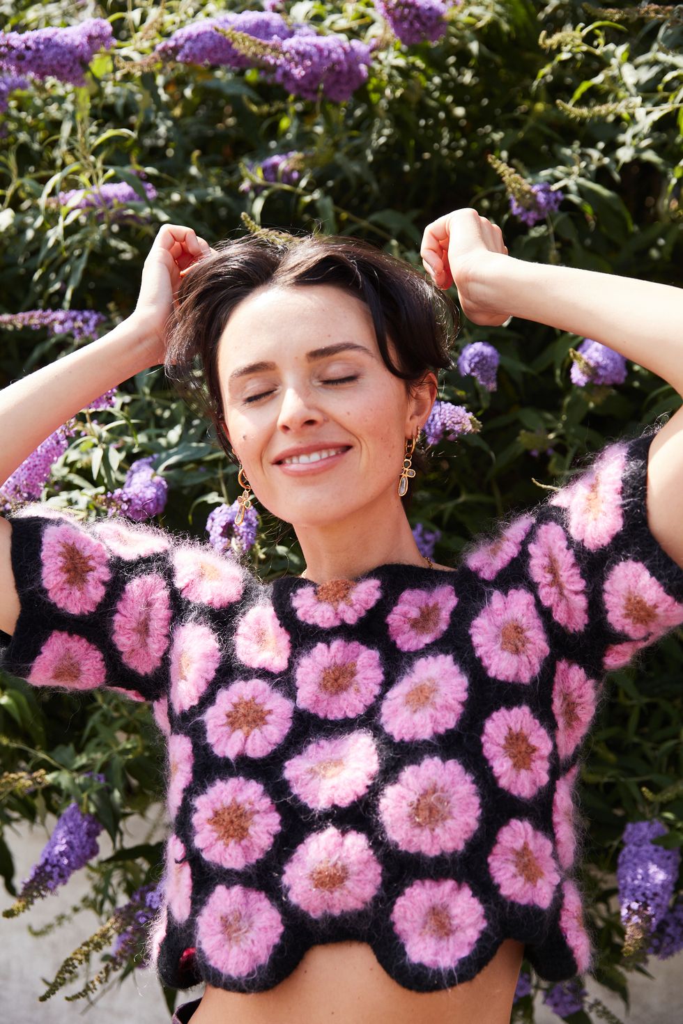 a brunette woman in a crocheted floral shirt