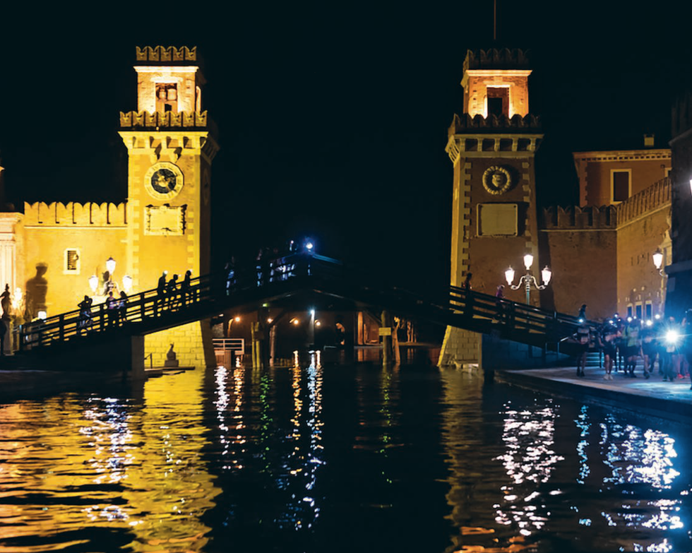 nighttime scene featuring historical architectural structures and a bridge over water