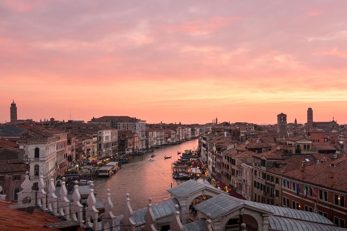 Onder een rozekleurige hemel varen gondolas door Veneti