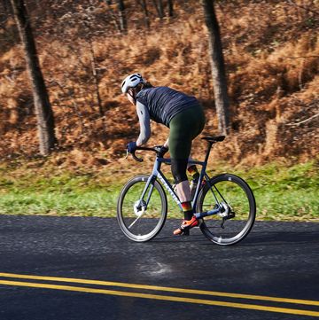 a person riding a bicycle on a road with trees on the side
