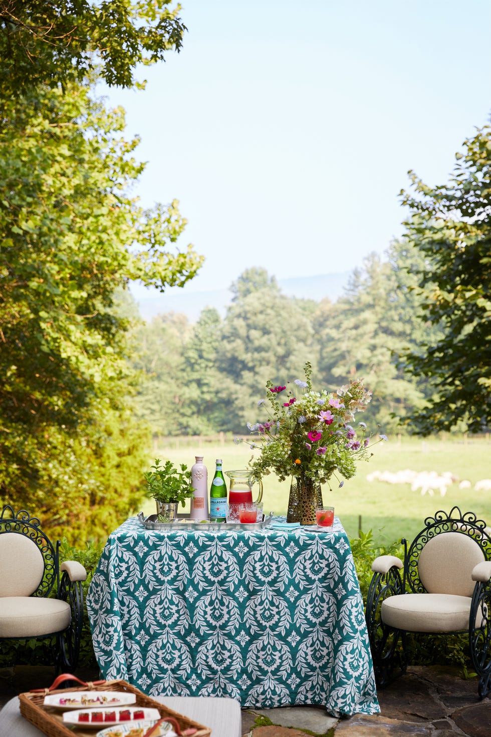 a table with chairs and bottles on it with trees in the back