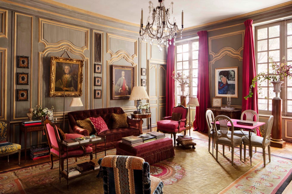 a living room with red velvet sofas and portraits on the walls