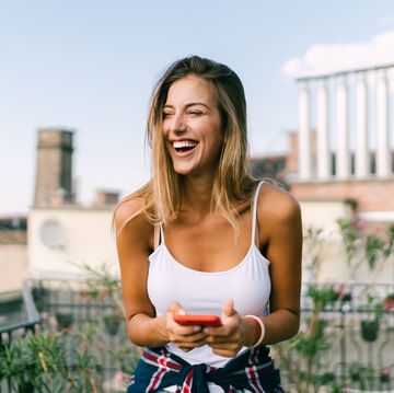 a woman smiling and holding a phone
