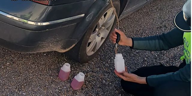 a person holding a bottle and a car