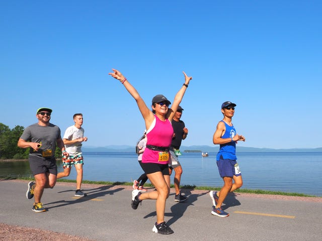 a group of people running on a road by the water