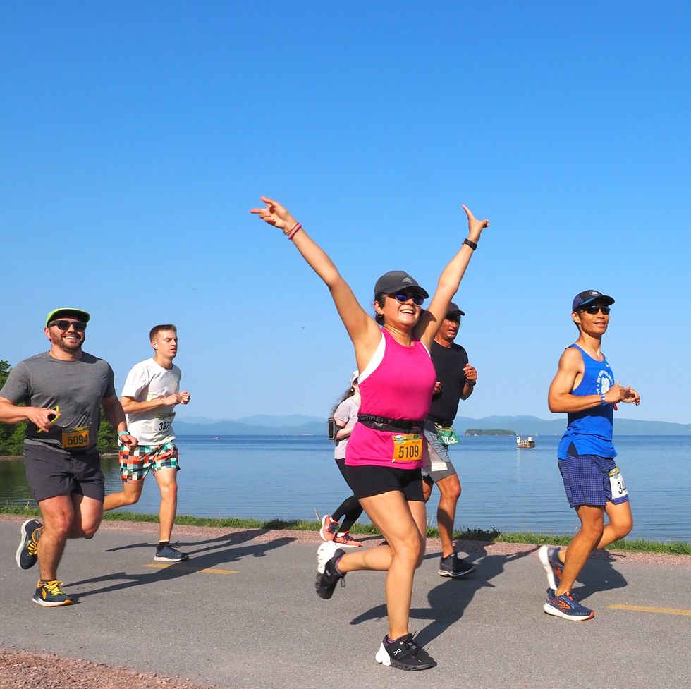 a group of people running on a road by the water