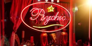 een winkelraam met een rood lichtbord waarop psychic te lezen valt en diverse versieringen
