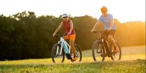 very happy smiling fit sporty couple on e mountain bikes on sunny afternoon in grassland