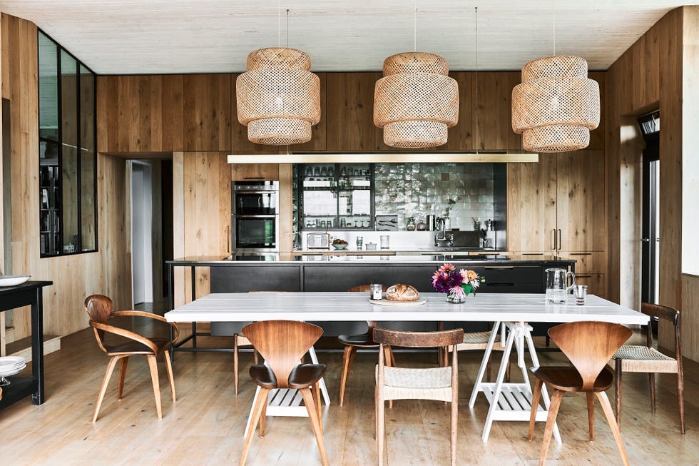 timber clad modern kitchen diner with rattan pendants over kitchen table and glazed zellige tiles