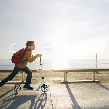Boy riding scooter on beach promenade at sunset Boy riding scooter on beach promenade at sunset