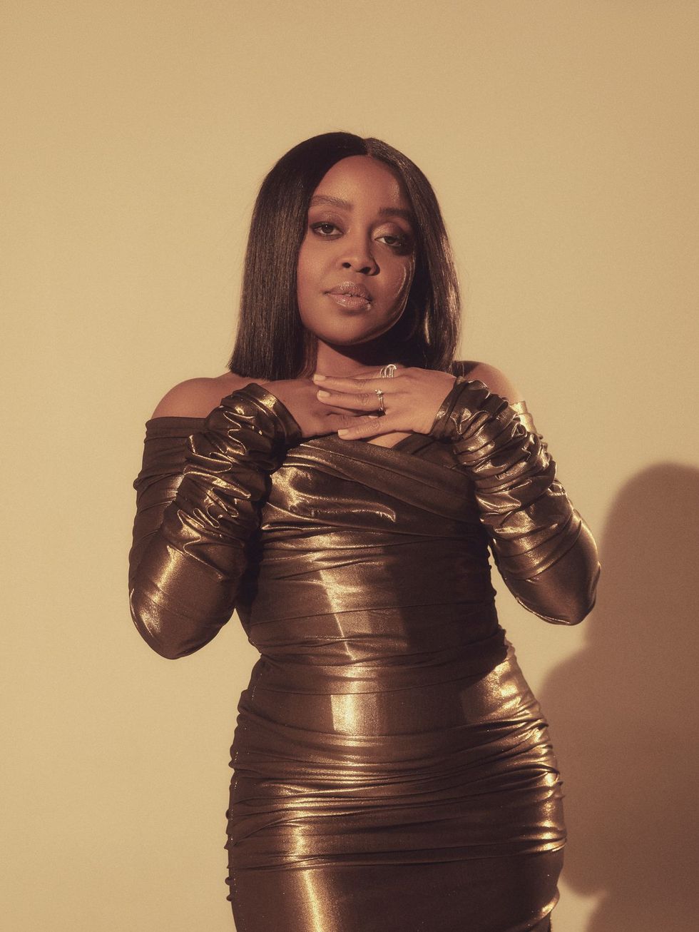 quinta brunson wears a bronze dress and poses for the camera