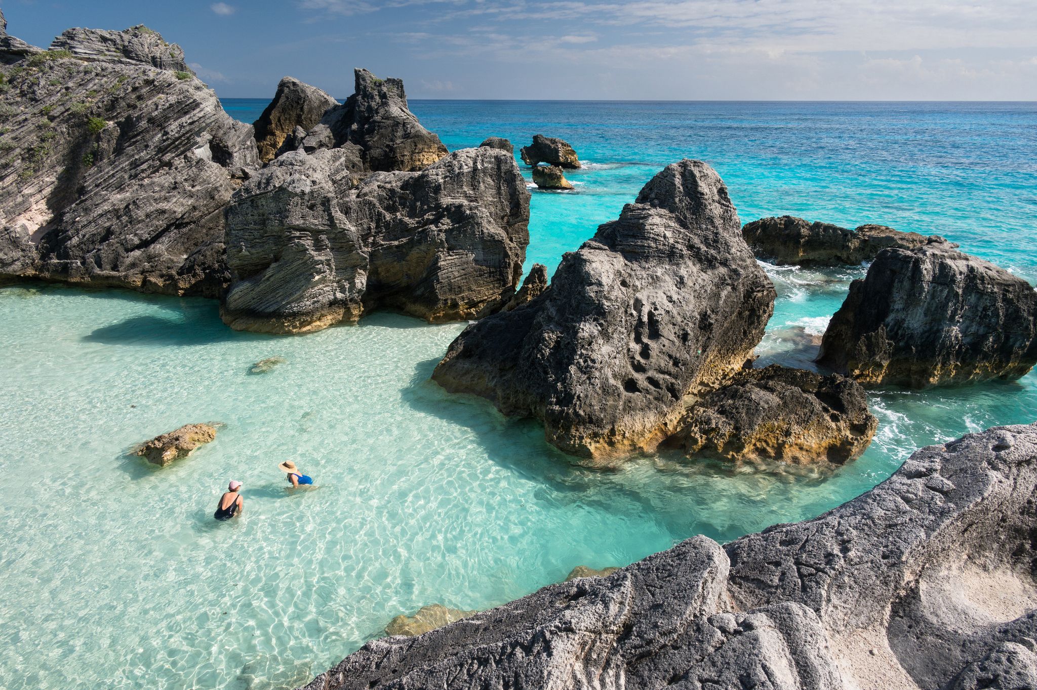 tourists enjoying the crystal clear waters of the atlantic ocean at the world famous horseshoe bay beach, bermuda