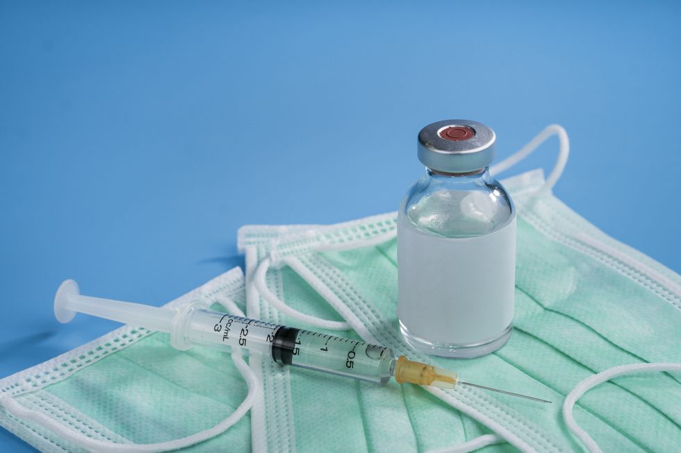 vial of coronavirus vaccine with syringe and mask