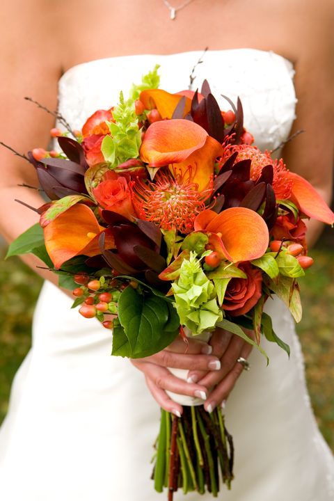 female bride holding a bouquet of beautiful fall colored flowers ready to walk down the aisle flowers are in focus