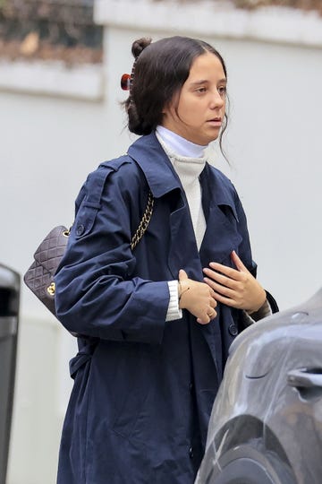 la hija de la infanta elena con una gabardina azul y el pelo recogido en un mono
