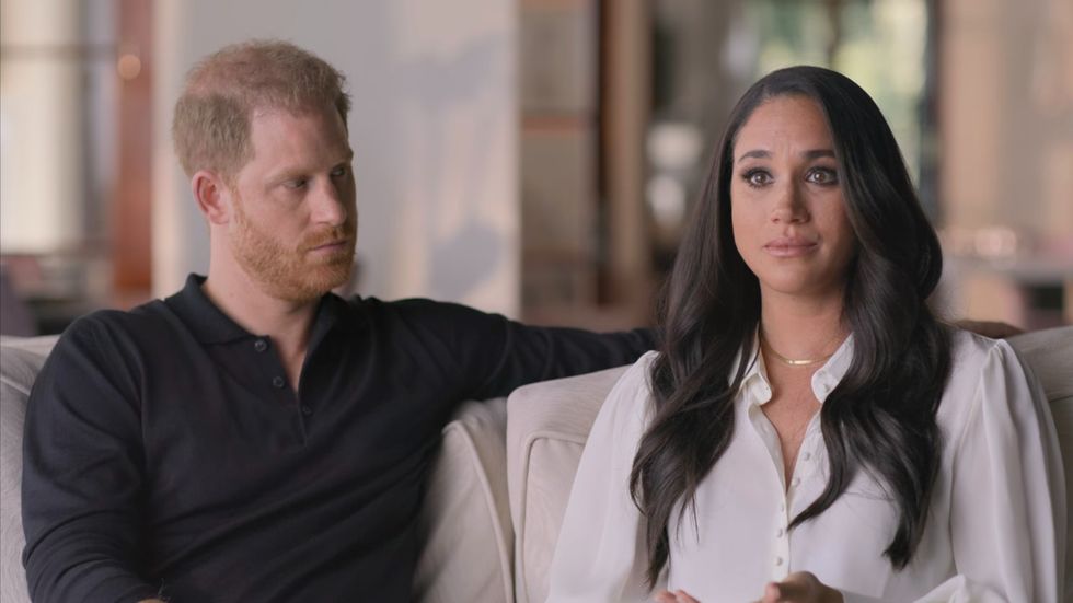 harry and meghan sit next to each other as meghan cries