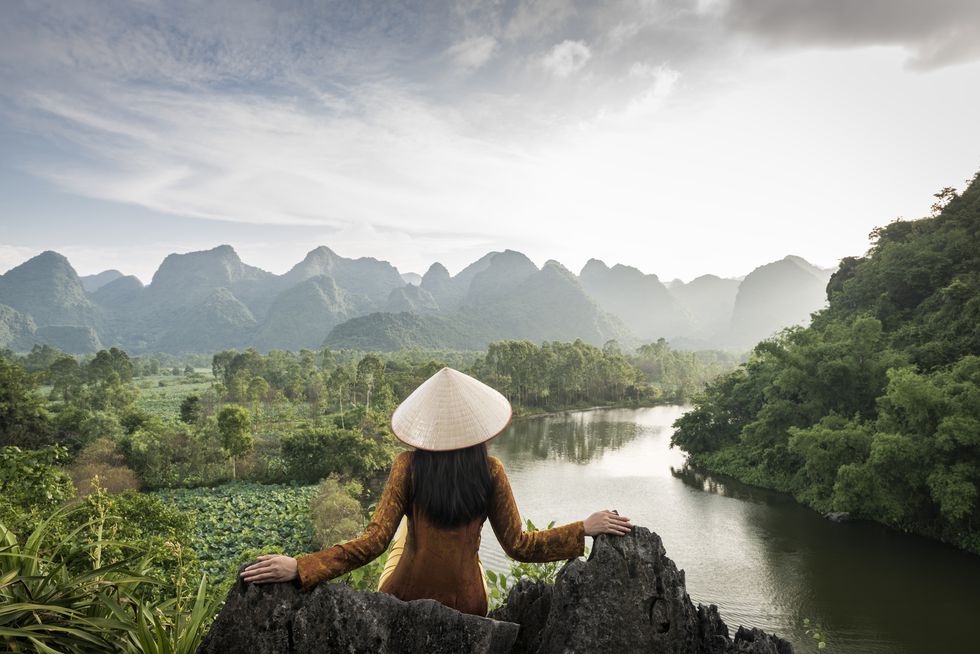 vietnamese woman on hilltop in front of mountains