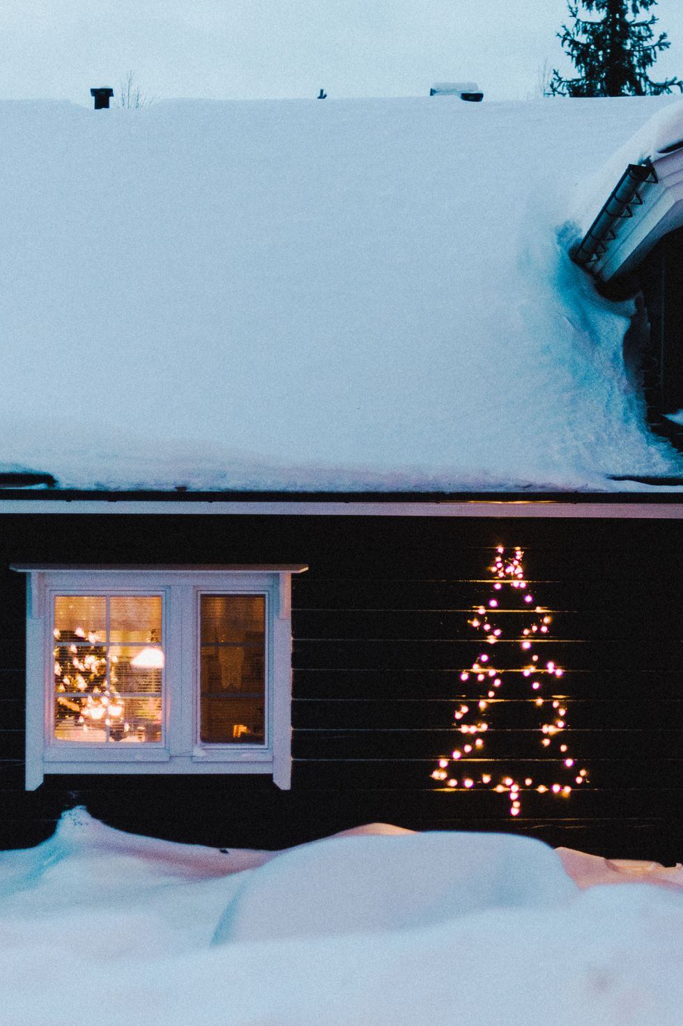 a view of a christmas tree made of lights on the side of a house stock photo