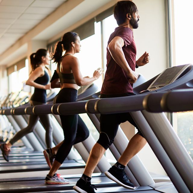 view of a row of treadmills in a gym with people