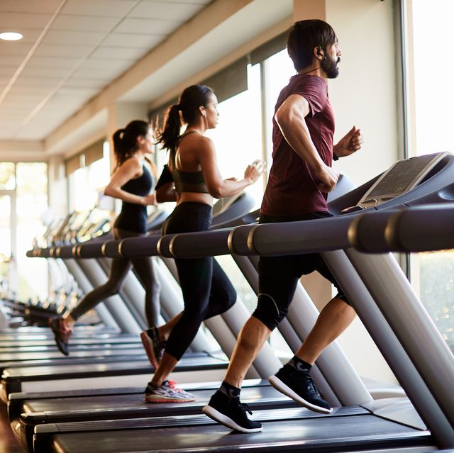 view of a row of treadmills in a gym with people