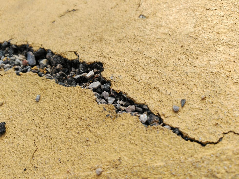 view of cracked concrete road and gravel on road surface
