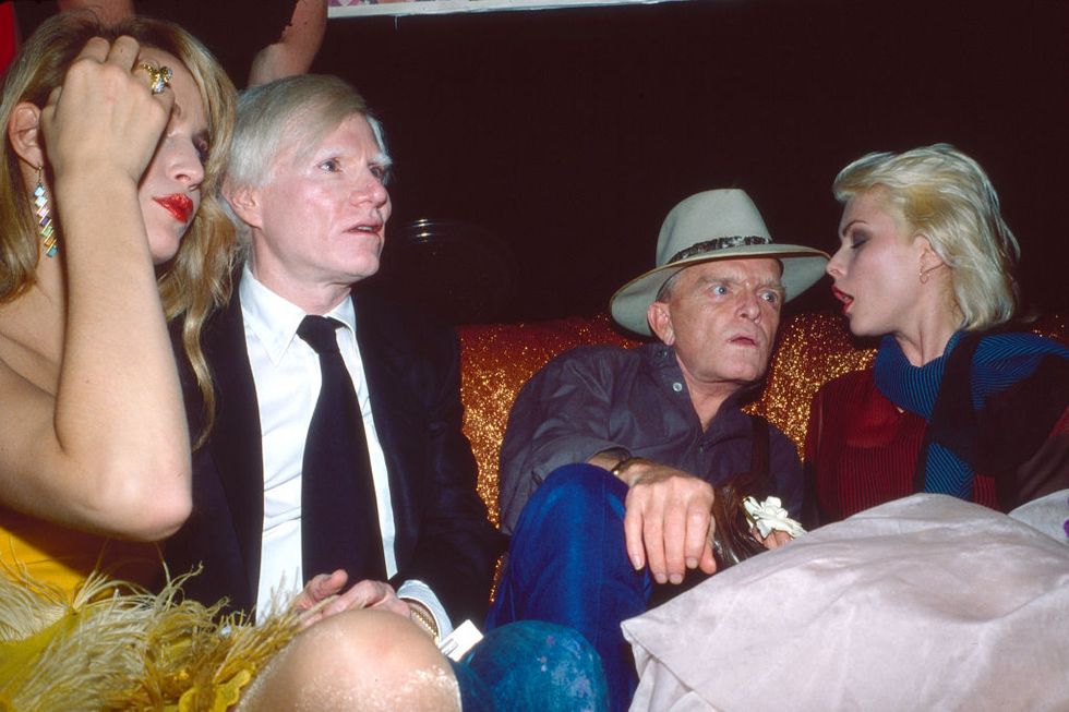 andy warhol, truman capote, and debbie harry all sitting at a table at a nightclub