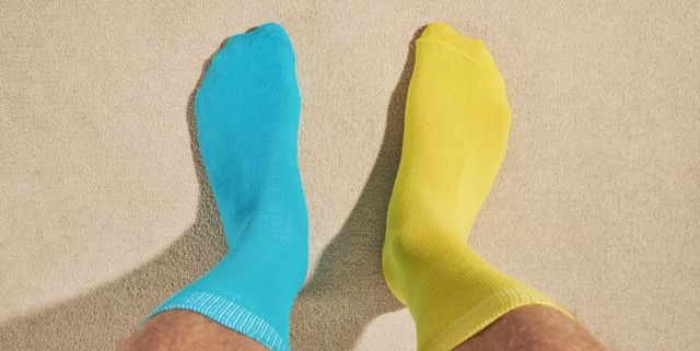 pov view of mans feet wearing odd socks, blue and yellow